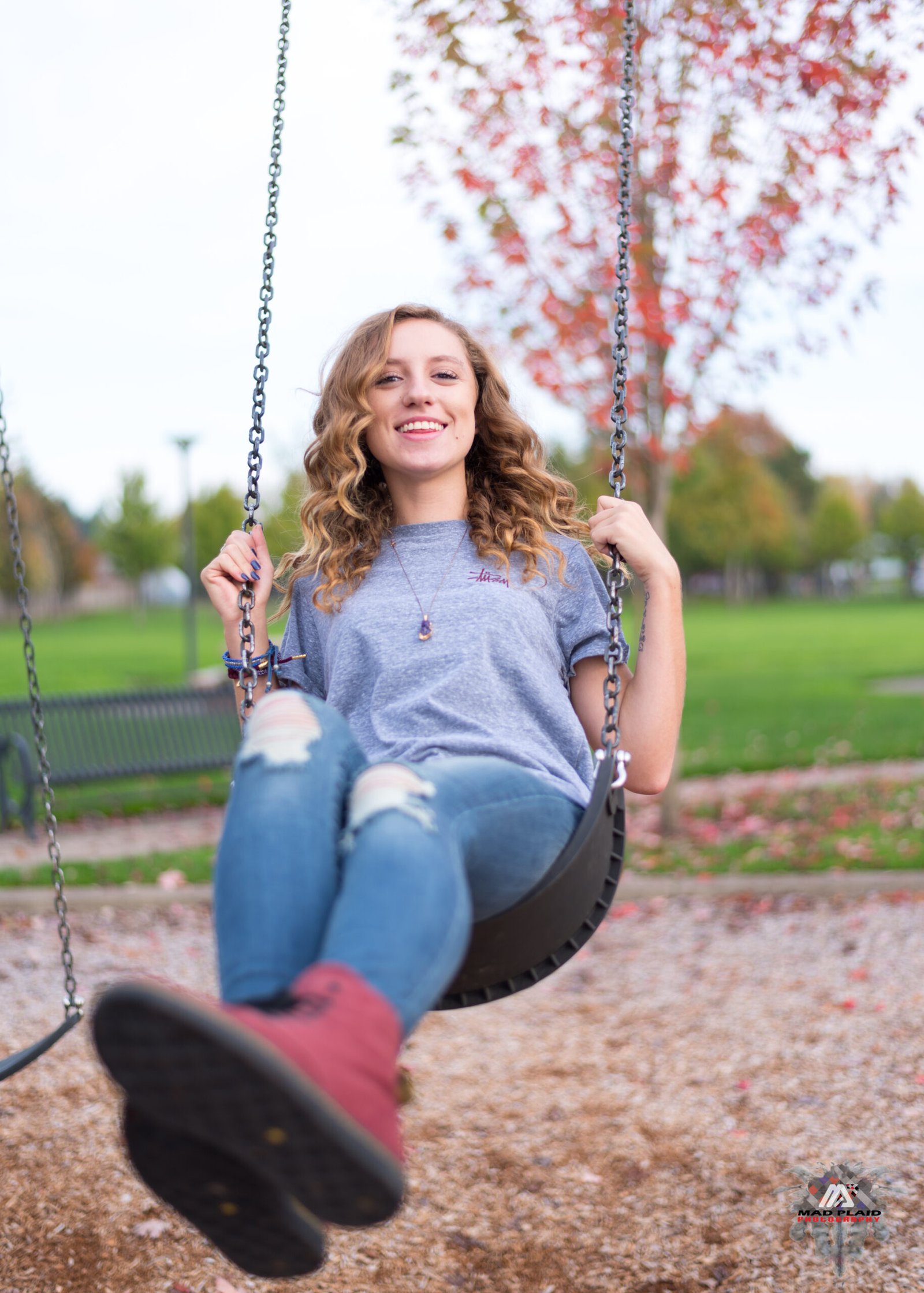 Portrait photography for senior photos. Girl on swing having fun, and laughing.